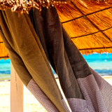 Set aus khaki Fouta und hellgraues Strandtuch am Sonnenschirm aufgehängt