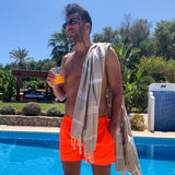Mann in Shorts mit beigem Hamamtuch auf der Schulter am Pool