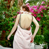 Frau im Garten, eingewickelt in ein rosa Fouta Strandtuch