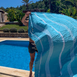 Mann mit aquablauem Strandtuch in der Nähe des Pools