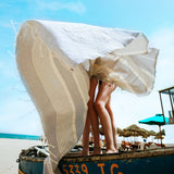 zwei Mädchen in Bikinis am Strand, bedeckt mit einem hellgrauen Fouta Strandtuch