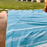 ein aquablaues XXL Hamamtuch Fouta auf einem Bett im Freien