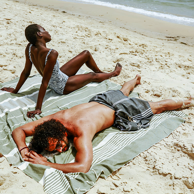 ein Paar beim Sonnenbaden am Strand auf einem khakifarbenen XXL Strandtuch