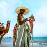 eine Frau am Strand mit einem olivgrünen Hamamtuch Strandtuch vor den Kamelen