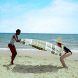 zwei Mädchen am Strand, die ein olivgrünes Strandtuch fouta in den Sand legen