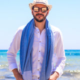 Mann mit Hut und Sonnenbrille in marineblauem Hammamtuch am Strand