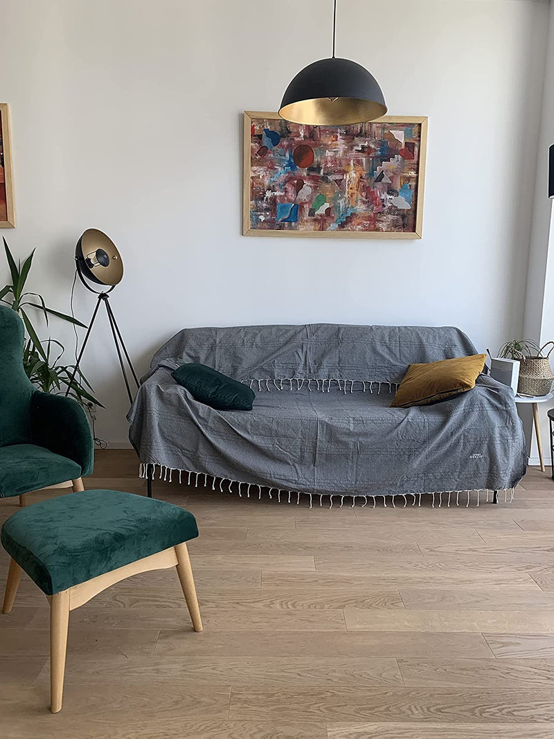 eine dunkelgraue Decke auf einer Couch im Wohnzimmer mit einem Gemälde an der Wand