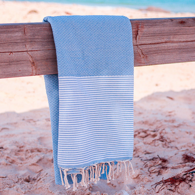  blaues Strandtuch auf einem Stück Holz am Strand aufgehängt
