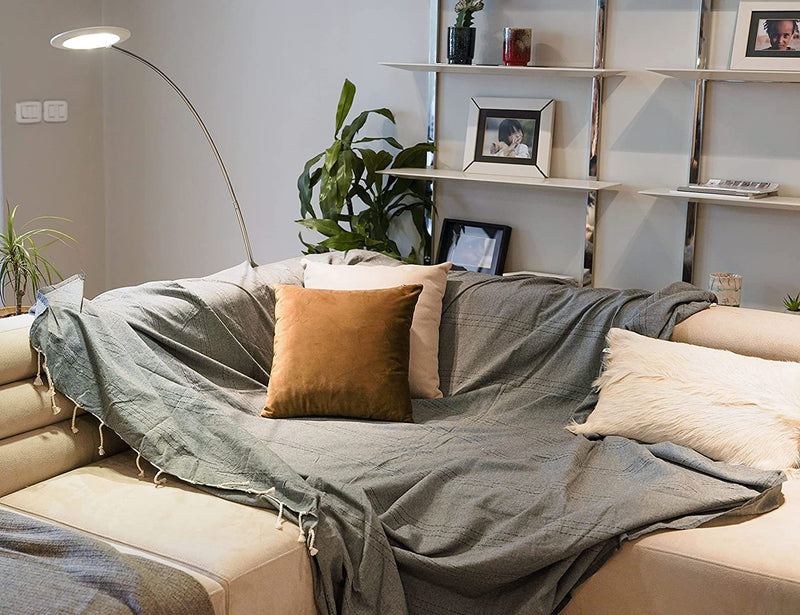 eine graue Sofaüberwurf mit Kissen auf einem L-förmigen beigen Sofa 