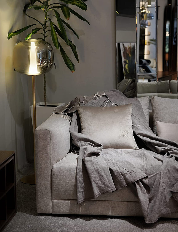 eine dunkelgraue Decke Sofaüberwurf  mit Quasten und grauen Kissen auf dem Sofa