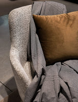 eine graue Sofaüberwurf mit Kissen auf einem grauen Sofasessel