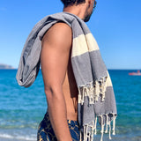 Mann am Strand mit blauem Hamamtuch auf der Schulter