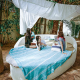 eine Gruppe von Mädchen die auf einem Bett mit einem aquablauen XXL hamamtuch im Freien faulenzen