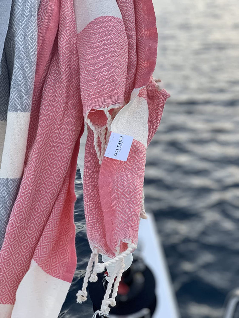 rosa Strandtuch und graue Fouta auf einem Boot
