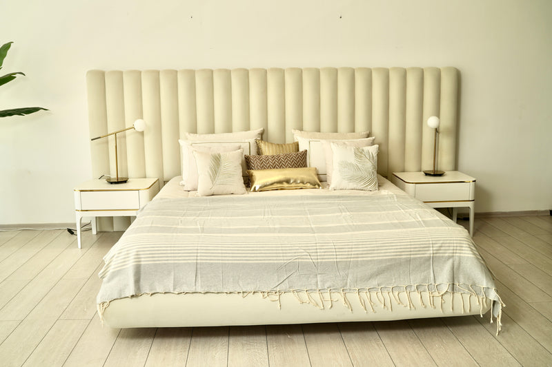 ein großes Bett, das mit einer hellgrauen Bettüberwurf decke bedeckt ist 